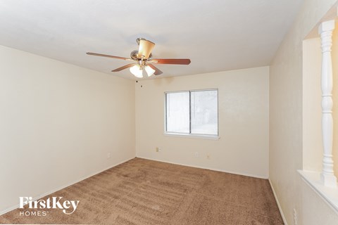 a living room with a carpet and a ceiling fan