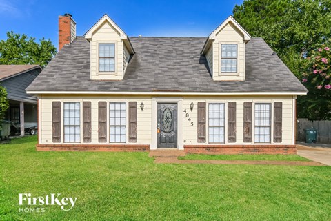 a white house with a gray roof and a lawn