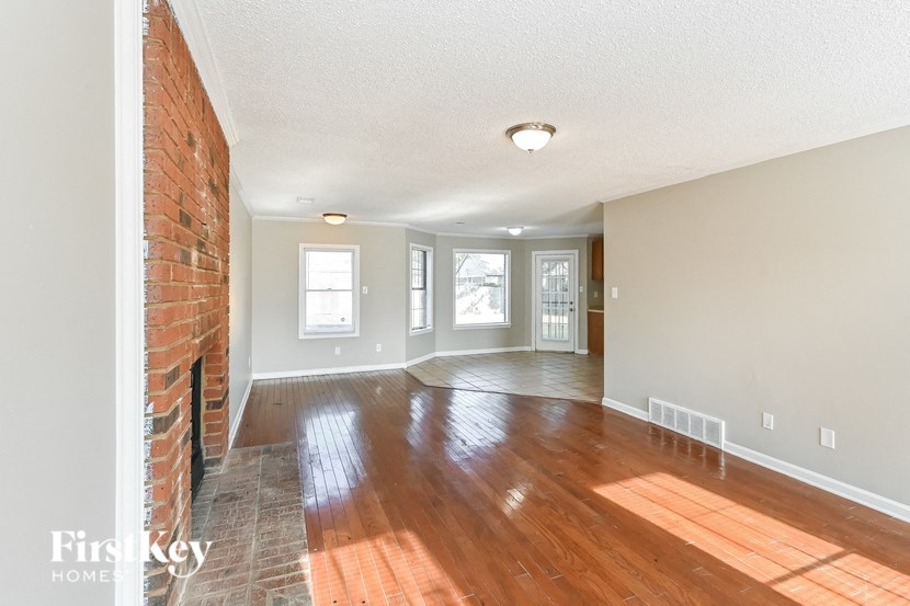 an empty living room with wood floors and a brick fireplace