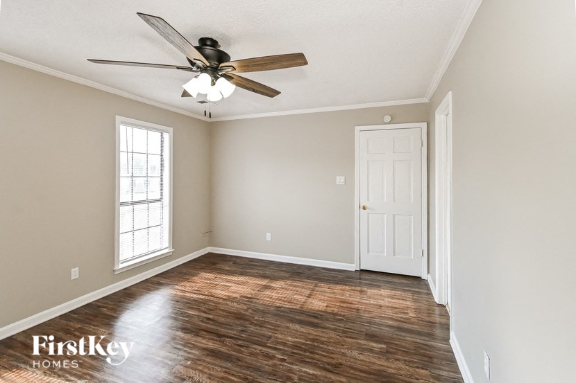 an empty living room with a ceiling fan and a white door