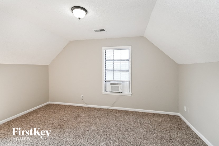 an empty bedroom with a window and carpeting