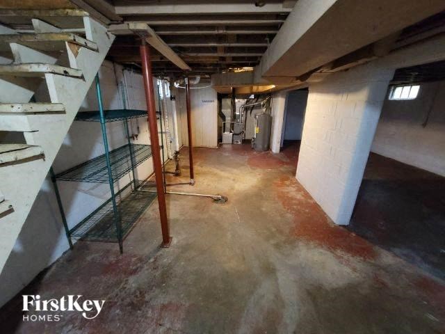 a dirty basement with stairs and a metal cage