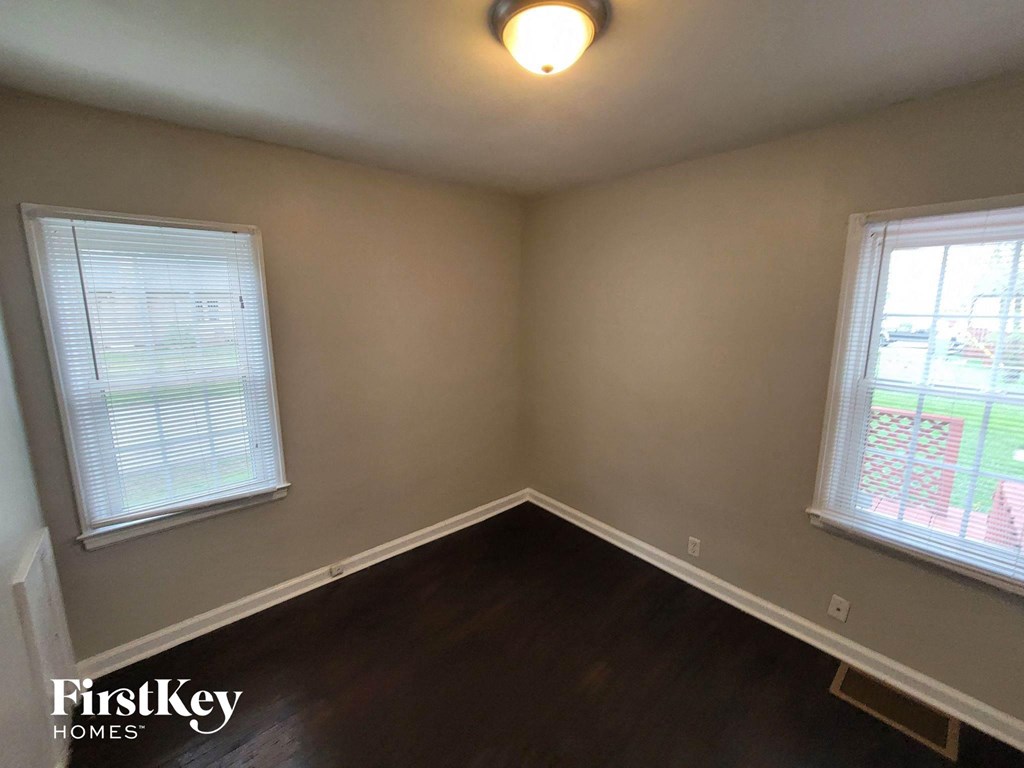 a small room with a wooden floor and two windows