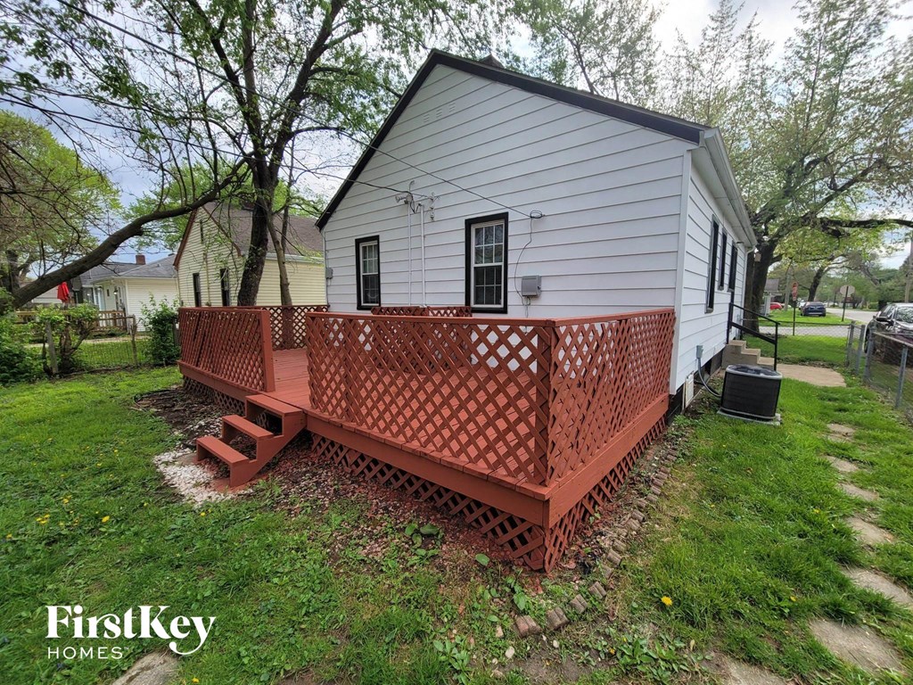 a small white house with a porch and a wooden fence