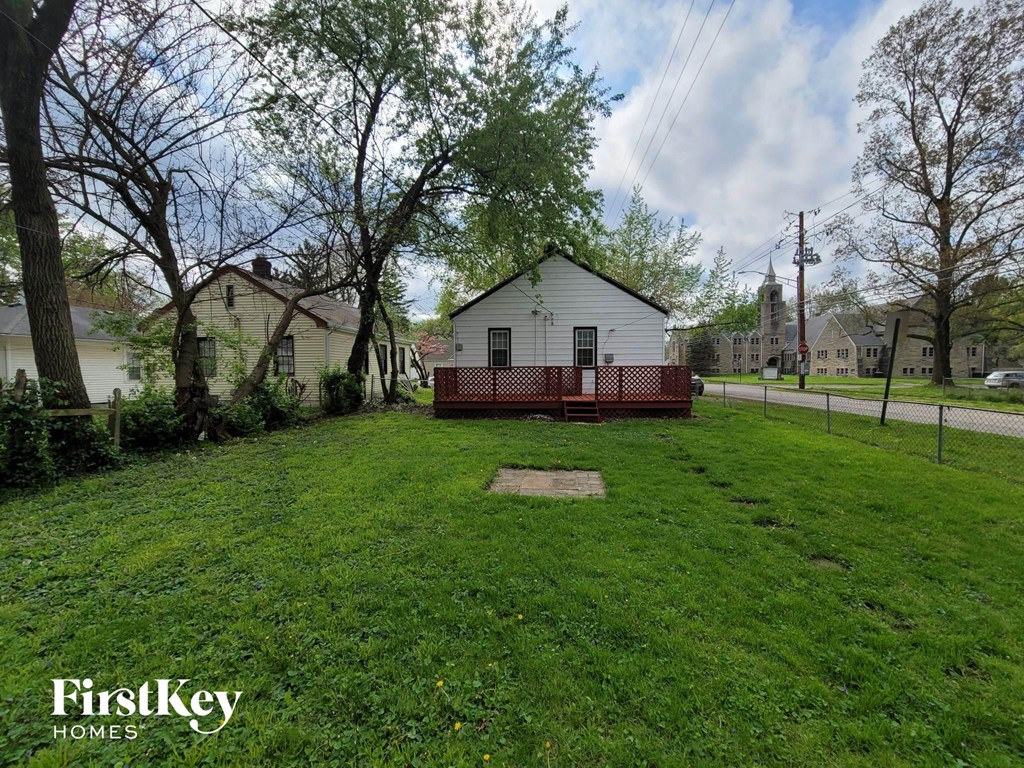 a yard with a white house with a red fence