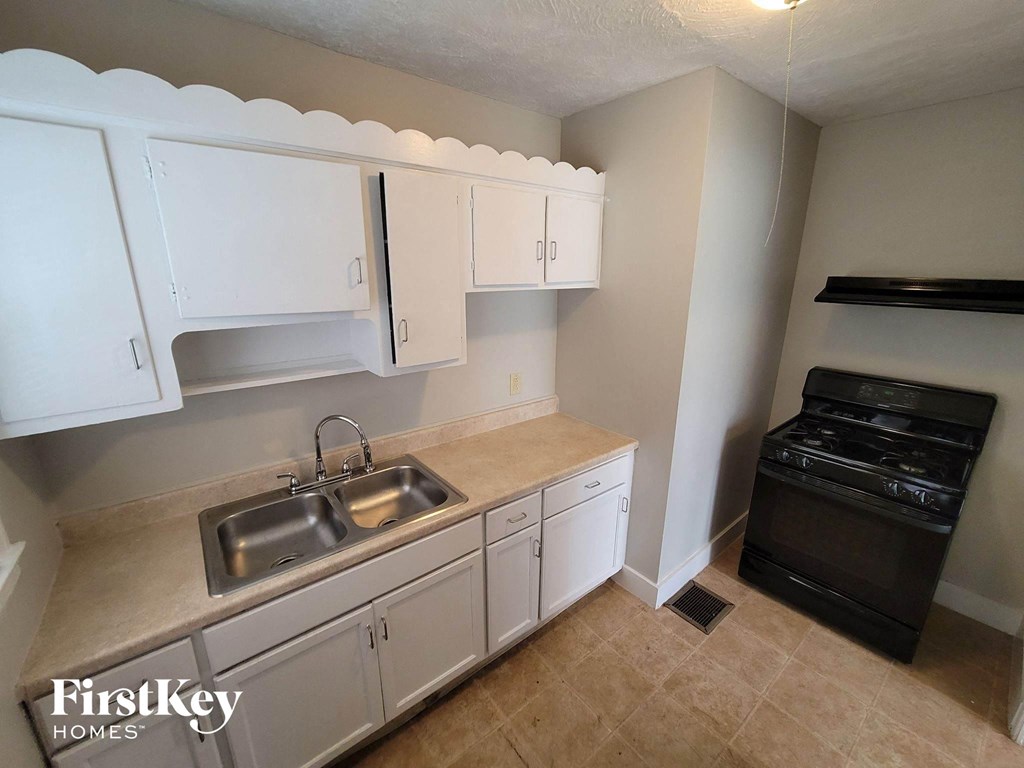 a kitchen with white cabinets and a sink and a stove