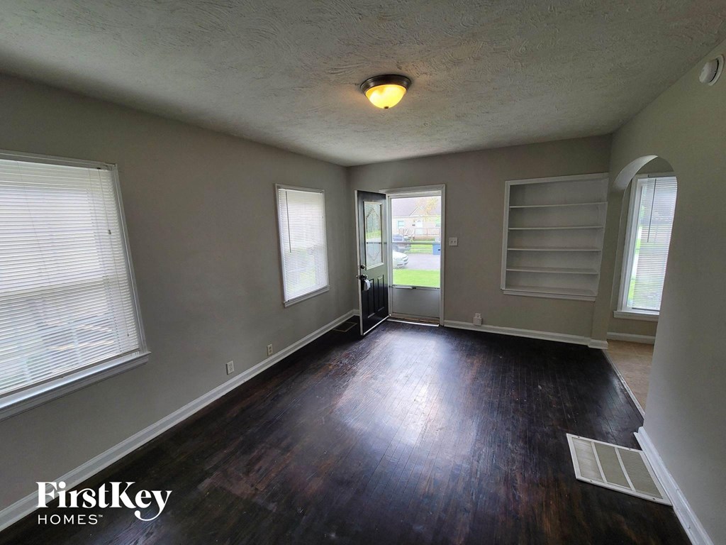 an empty living room with a hard wood floor and a window