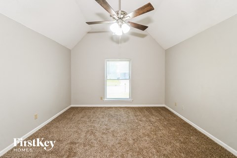 an empty room with a ceiling fan and a window