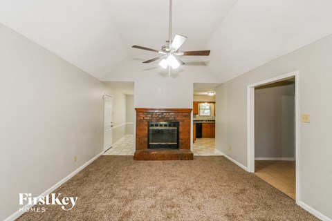 an empty living room with a fireplace and a ceiling fan