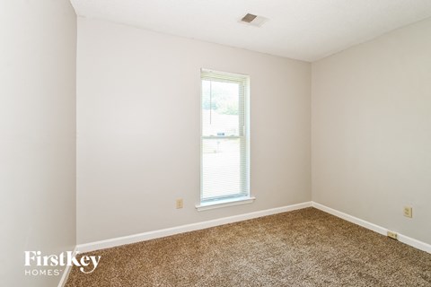 a bedroom with white walls and carpet and a window