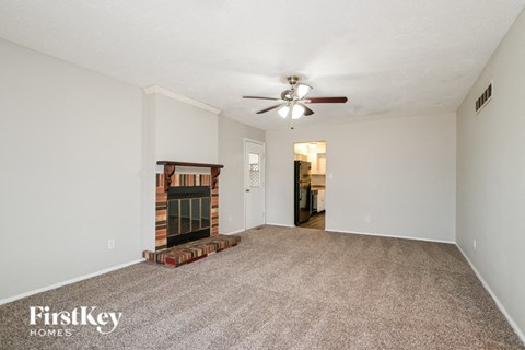 A spacious room with a fireplace and a ceiling fan.