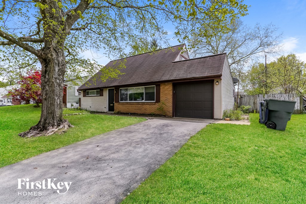 a small house with a driveway and a tree
