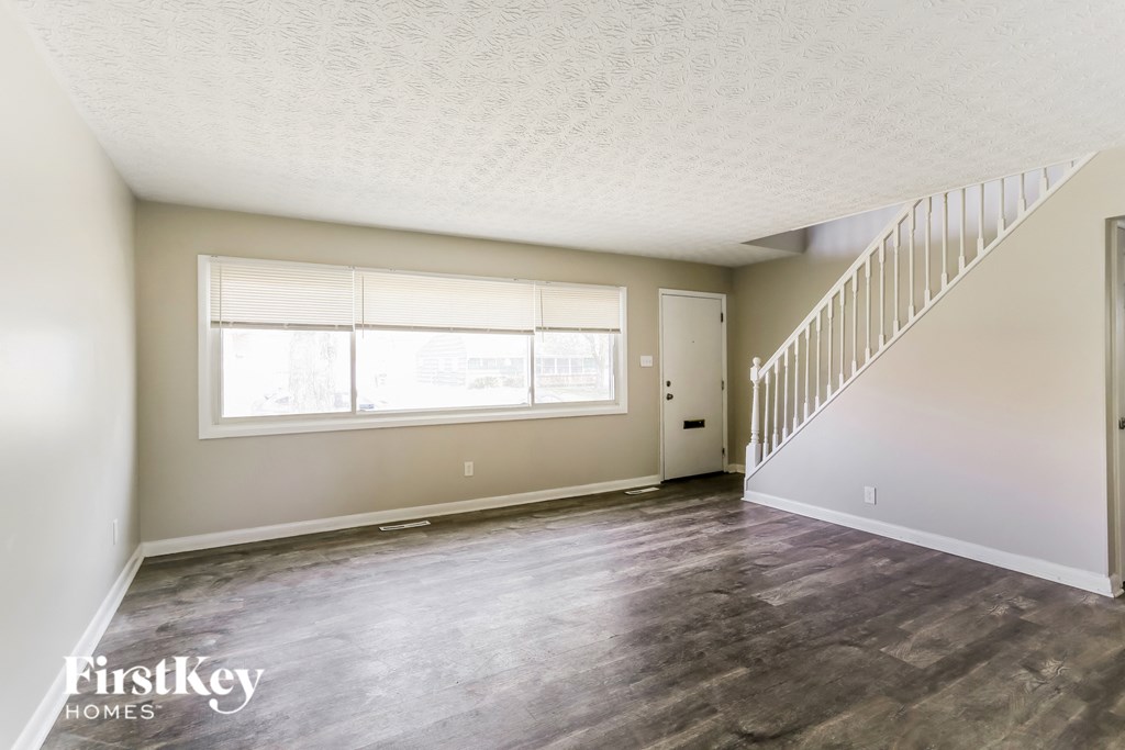 an empty living room with a large window and a staircase