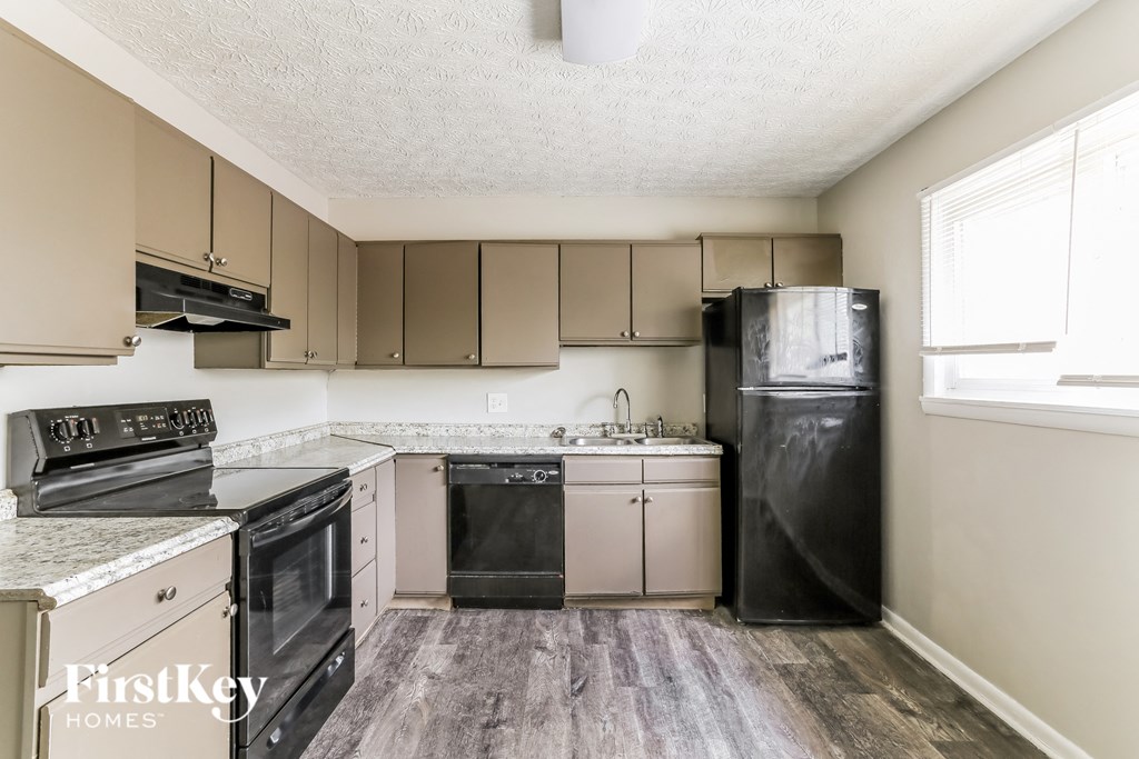 an empty kitchen with black appliances and white cabinets