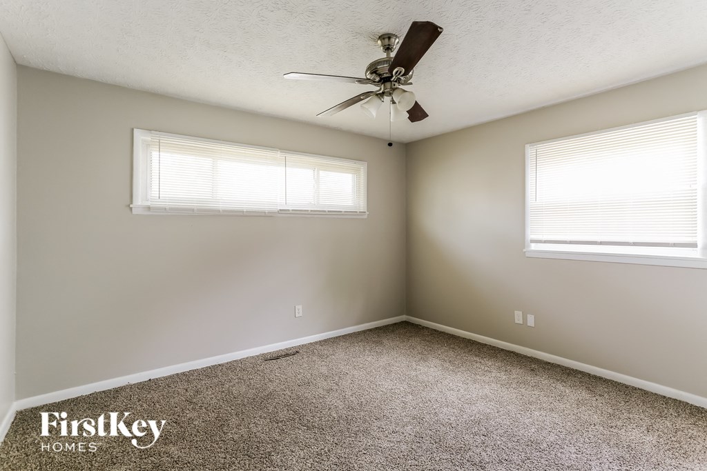 a bedroom with two windows and a ceiling fan