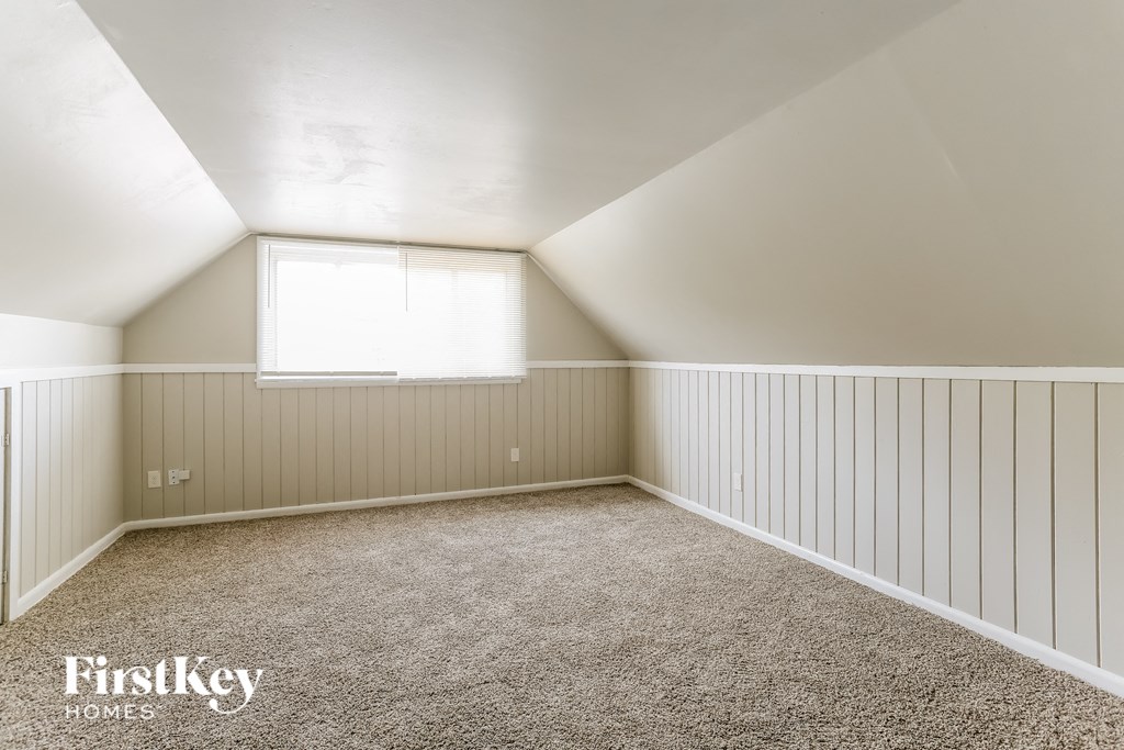 a small attic bedroom with white wainscoting and a window