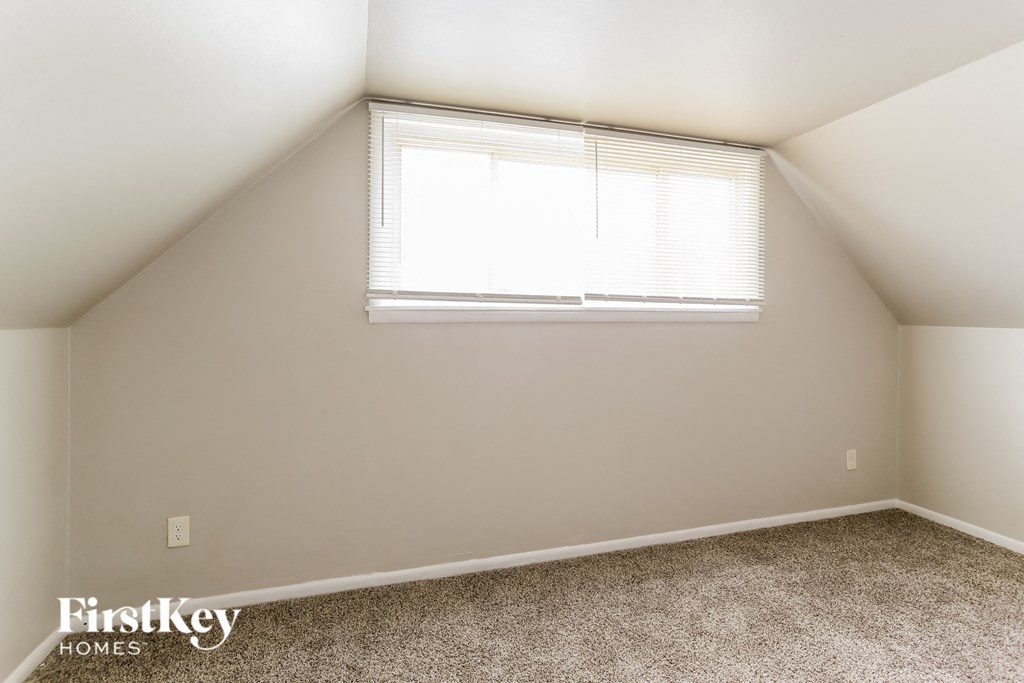 the bedroom of an attic with a window and carpet