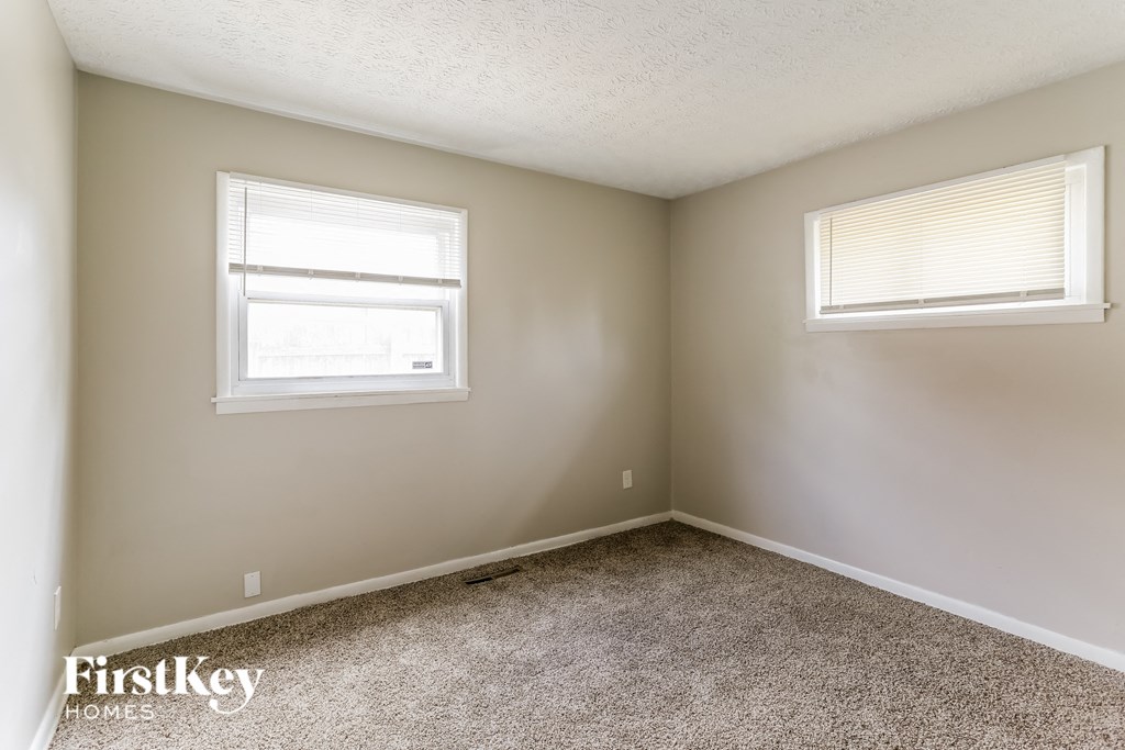 a bedroom with two windows and a carpeted floor