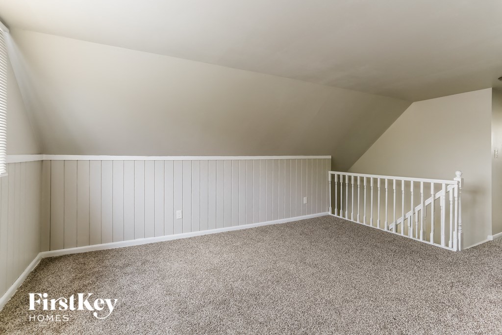 a attic bedroom with a white railing and carpeted floor