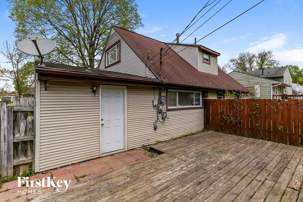the backyard of a house with a wooden deck and a white garage door
