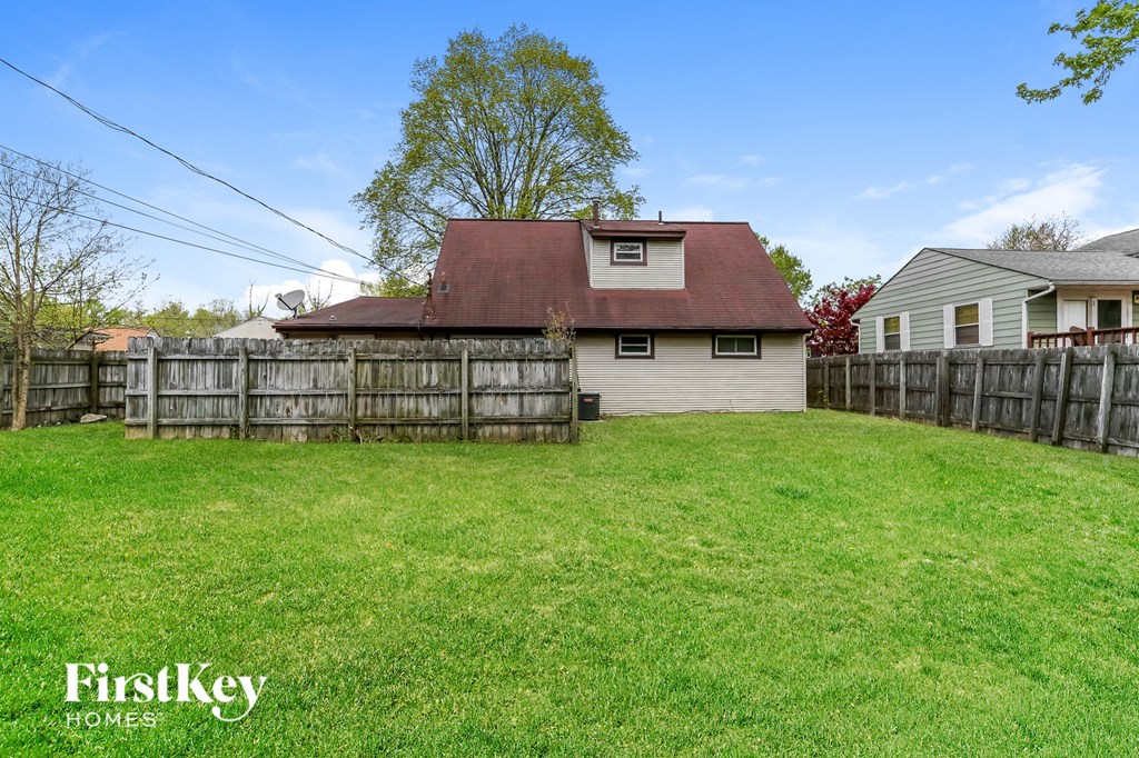 a backyard with a fence and a house with a red roof