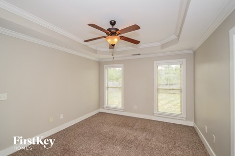 a living room with a ceiling fan and a carpet