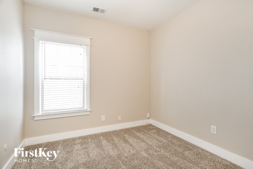 the bedroom of a home with a carpeted floor and a window