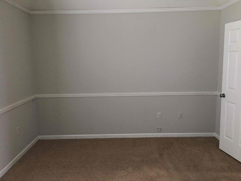 A room with a white door and carpeted floor.