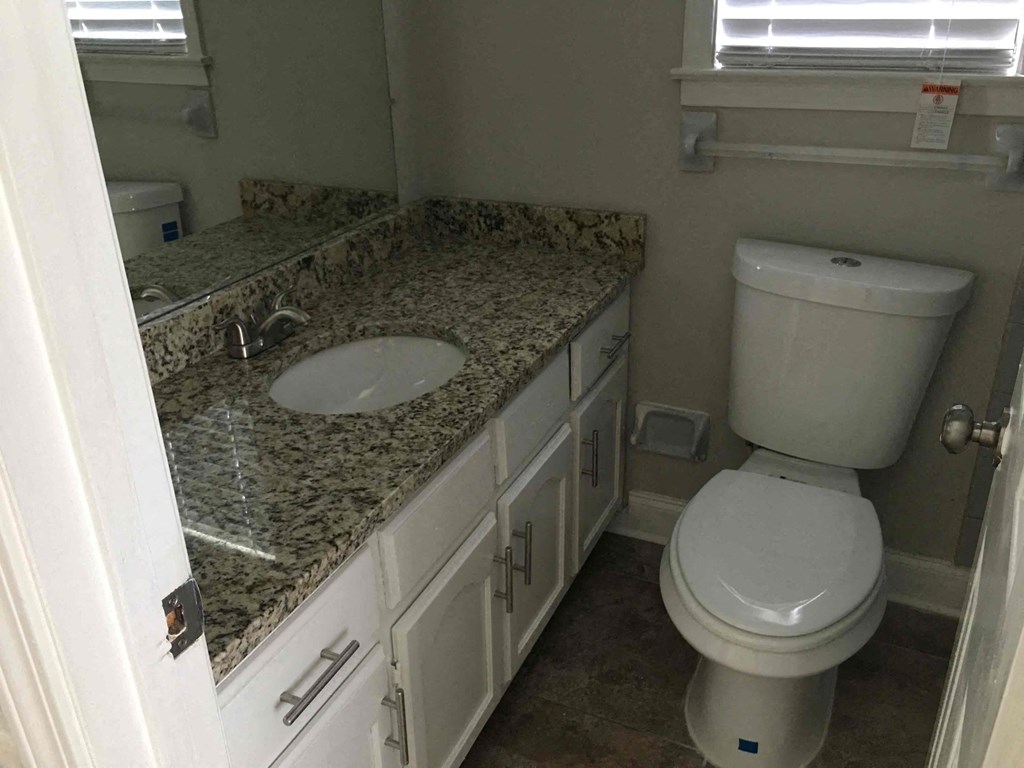A bathroom with a granite countertop and white fixtures.