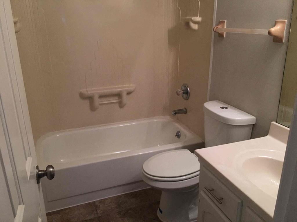 A white toilet sits next to a white bathtub in a bathroom.