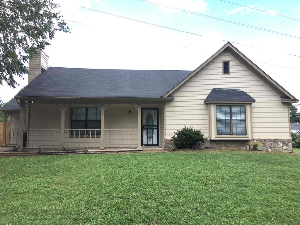 A house with a black roof and a green lawn in front.