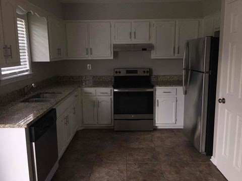 A kitchen with white cabinets and a black stove top oven.