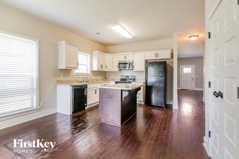 A kitchen with wooden floors and a refrigerator.