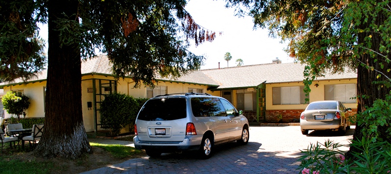 A silver minivan is parked on a driveway in front of a house.