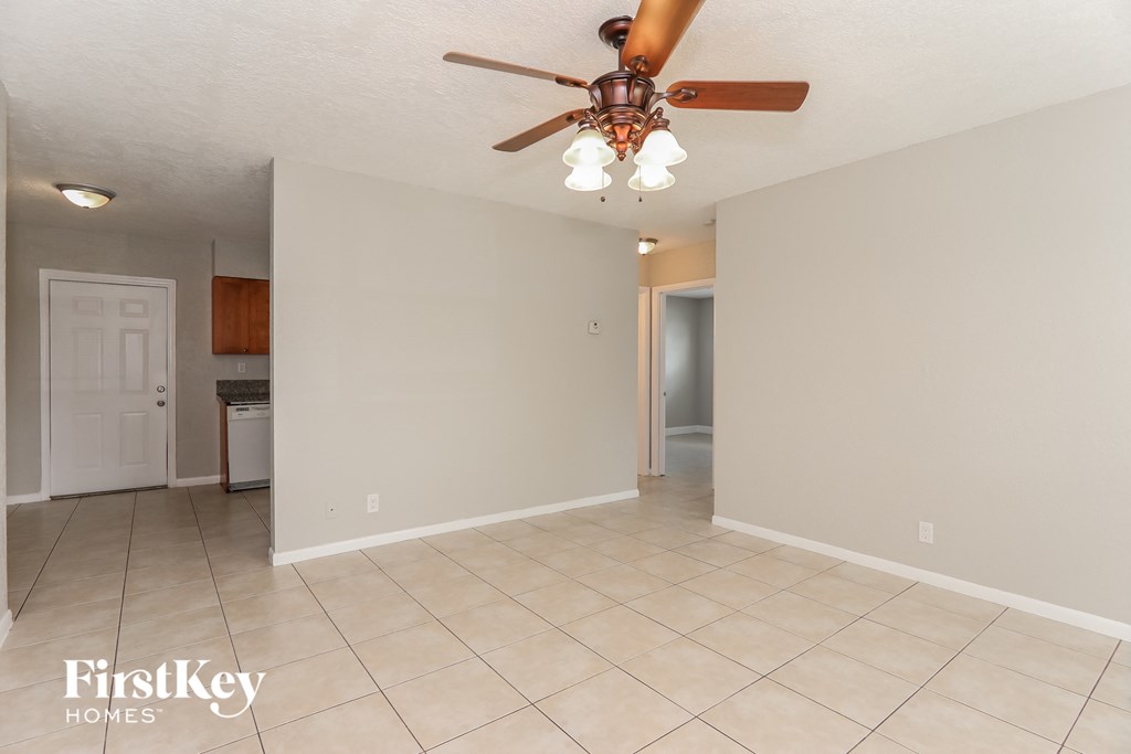 an empty living room with a ceiling fan and a tile floor