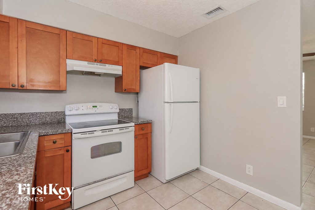 a kitchen with white appliances and wooden cabinets and a refrigerator