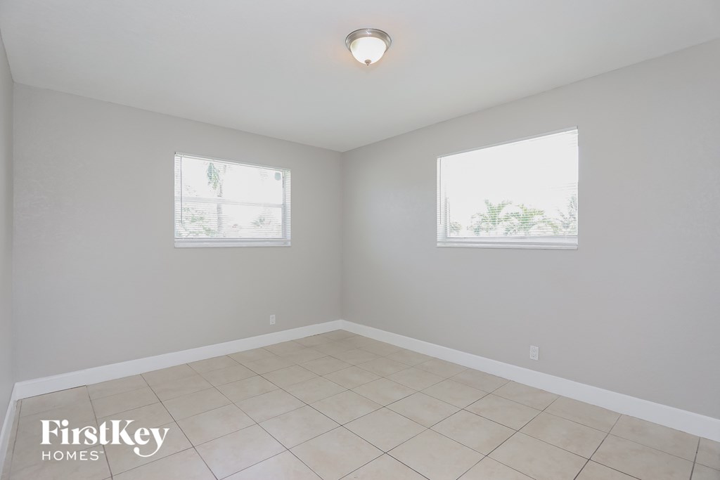 an empty room with two windows and a tiled floor
