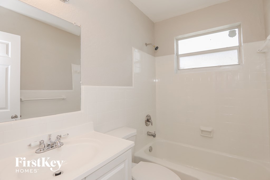 a white bathroom with a tub and a sink and a toilet