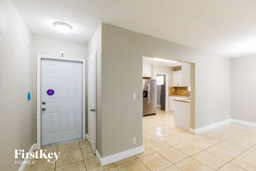 a hallway with a white door and a tiled floor