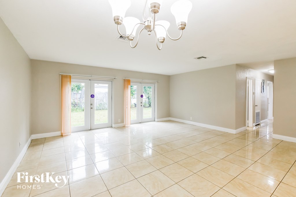 an empty living room with doors and a chandelier