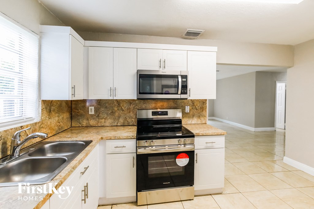a kitchen with white cabinets and a stove and a sink
