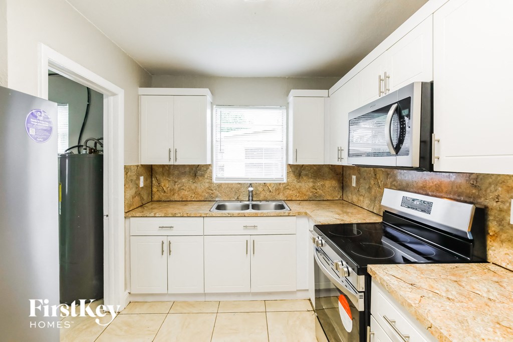 a kitchen with white cabinets and appliances and a sink