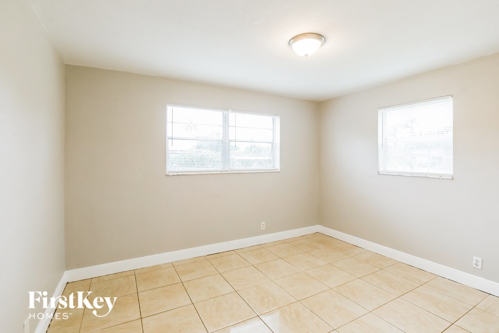 an empty room with a tiled floor and two windows