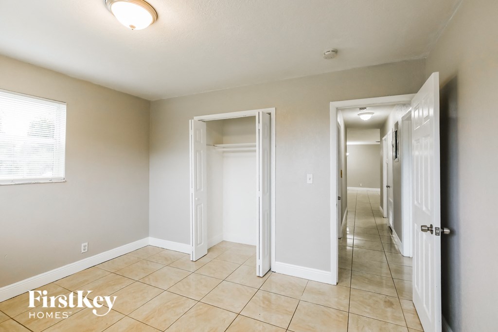 a hallway with white doors and tiled floors and a hall way with closets