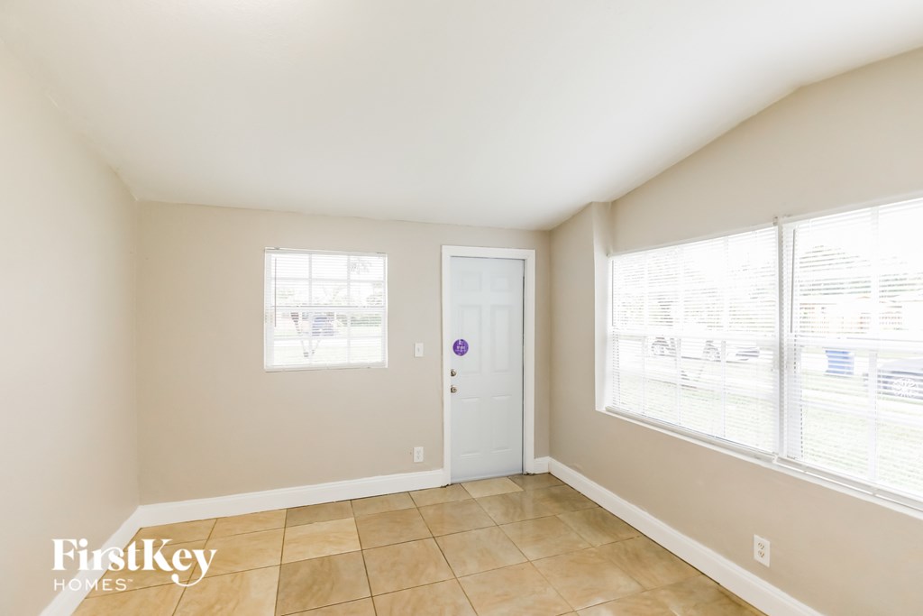 the living room of a home with large windows and a white door