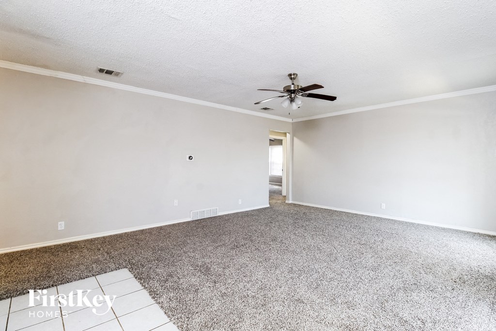 an empty living room with carpet and a ceiling fan