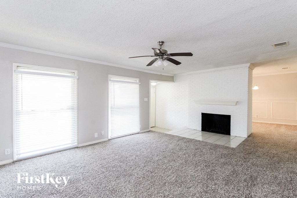 an empty living room with a ceiling fan and a fireplace