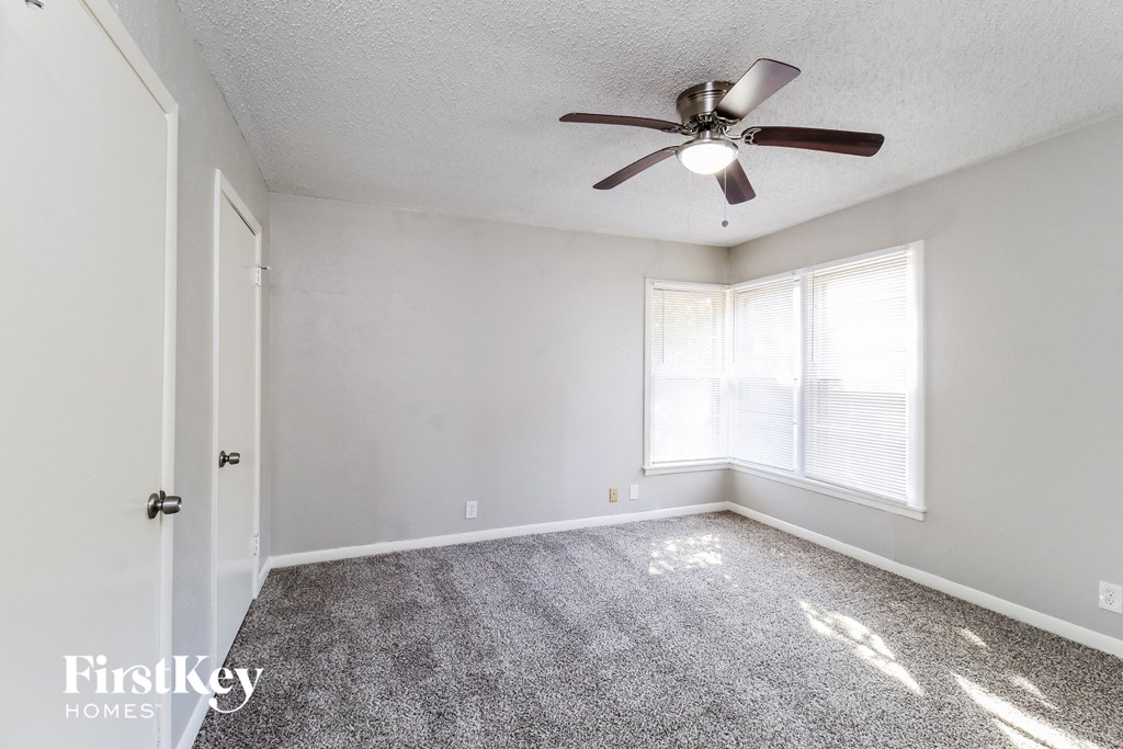 an empty bedroom with a ceiling fan and a window