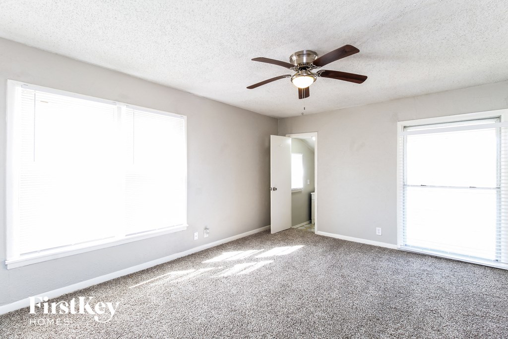 an empty living room with a ceiling fan and two windows