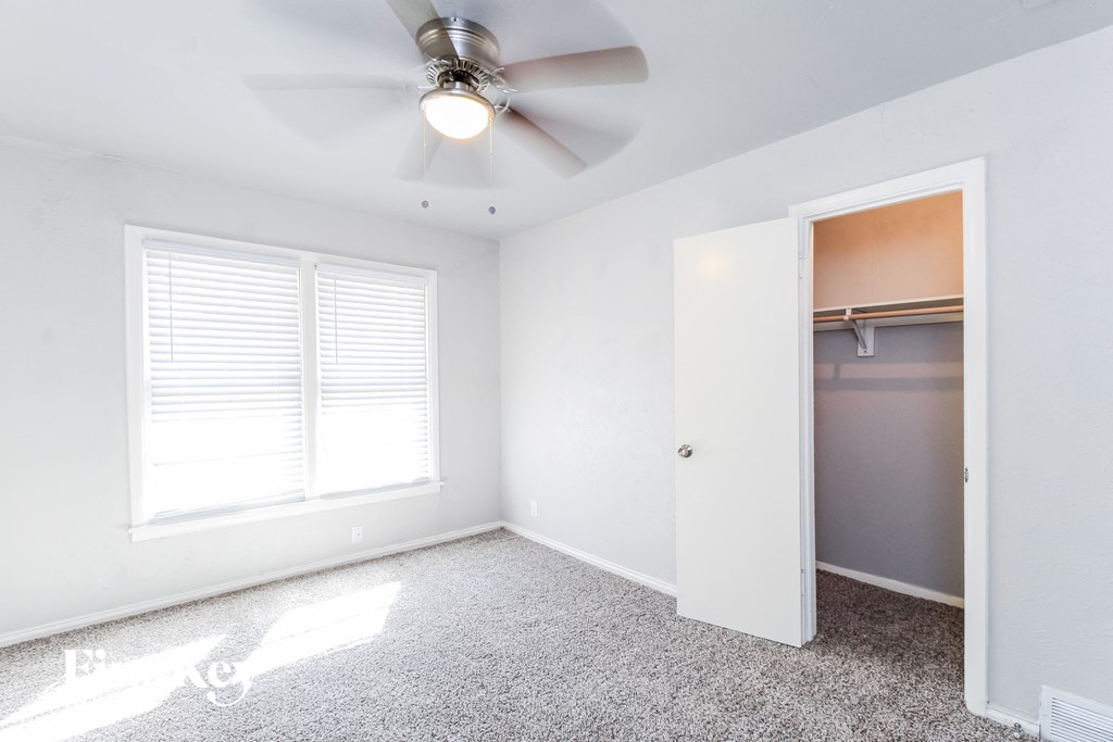 an empty bedroom with a ceiling fan and a closet